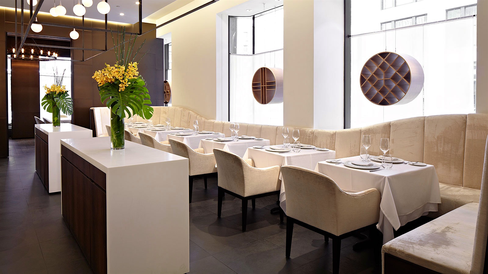 The elegant, light-filled dining room at Jungsik restaurant in New York, with a subdued light color palette contrasting with dark wood panels